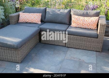 Moderne Gartengestaltung im Freien Terrasse mit Acryl Rattan Essmöbel mit Tisch und Stühlen, orange Kissen, lucent Kupfer Schiefer Hochbetten UK Stockfoto