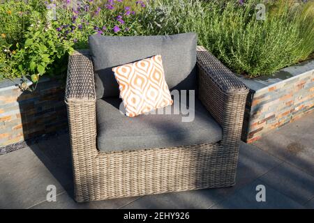 Moderne Gartengestaltung Terrasse im Freien mit Acryl Rattan Essmöbel mit Tisch und Stühlen, orange Kissen, lucent Kupfer Schiefer Hochbetten UK GB Stockfoto