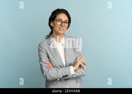 Selbstbewusste Geschäftsfrau, lächelnd, Blick auf die Kamera stehend mit gekreuzten Armen isoliert im Studio. Stockfoto
