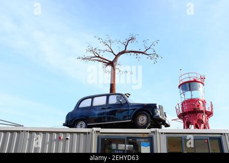 LONDON - 20th. FEBRUAR 2021: Trinity Booy Wharf. Taxi und Baumskulptur von Andrew Baldwin über dem Orchard Cafe. Stockfoto