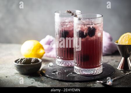 Erfrischende Blackberry Lemonade mit Eis in Kristallgläsern auf grauem Hintergrund Stockfoto