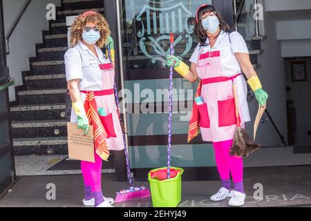 Las Palmas, Gran Canaria, Kanarische Inseln, Spanien. 20th. Februar 2021. Obwohl der einmonatige Karneval wegen der Covid-Beschränkung abgesagt wurde, kommen die Leute immer noch in den Geist, wie diese beiden Frauen, die als Putzfrauen am Strandprom in Las Palmas entlang gehen. Kredit: Alan Dawson/Alamy Live Nachrichten. Stockfoto