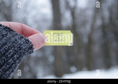 Der Frühling kommt. Eine Hand hält ein Schild mit der Inschrift Stockfoto