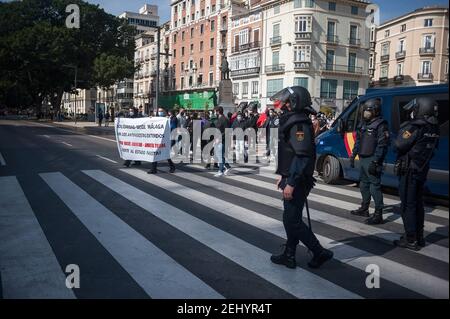 Malaga, Spanien. Februar 2021, 20th. Demonstranten marschieren entlang einer Straße, während Polizeibeamte während der Demonstration Wache stehen. Der Rapper Pablo Hasel wurde wegen der Verherrlichung des Terrorismus und der Beleidigung der spanischen Krone und der staatlichen Institutionen durch seine Lieder und Tweets verurteilt. Nach seiner Inhaftierung in den letzten Tagen sind in mehreren Städten heftige Unruhen ausgebrochen, als Reaktion auf die Meinungsfreiheit. Kredit: SOPA Images Limited/Alamy Live Nachrichten Stockfoto