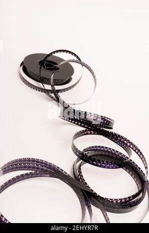 Die Filmrolle wird auf einer weißen Oberfläche mit sichtbaren kreativen Schatten abgelöst Stockfoto