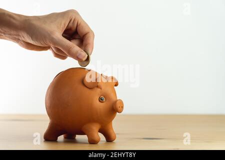 Frau Hand Putting Münze in Sparschwein, um Geld zu sparen und Finanzen zu planen. Stockfoto