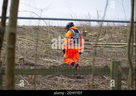 Aylesbury, Buckinghamshire, Großbritannien. 20th. Februar 2021. Ein Hundeführer von HS2 geht durch eine Haselnusspappice, bevor sie HS2 zerstört wurde. HS2 Ltd haben diese Woche ein Waldgebiet in Aylesbury übernommen und in den wunderschönen Spinney-Wäldern spät in der Nacht und bis in die frühen Morgenstunden riesige, reife Bäume gefällt. HS2 waren nicht in der Lage, eine Kopie der Natural England Lizenz, die sie haben müssen, damit diese Arbeit stattfinden, wie Fledermauswurzeln werden geglaubt, um in den Wäldern vorhanden sein. HS2 Sicherheitskräfte bewachen das Holz 24/7 und benutzen auch bösartige Hunde, um ihre nahe gelegenen comp zu bewachen Stockfoto