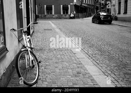 Straße und Fahrrad an der Wand in der Altstadt von Stockholm (Gamla Stan), Schweden. Urbane Szene, Schwarz-Weiß-Fotografie Stockfoto