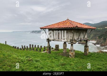 Horreo, ein traditioneller asturischer Getreidespeicher aus Holz und Stein an den Klippen mit Blick auf das Kantabrische Meer. Stockfoto