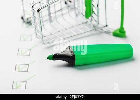 Supermarkt Warenkorb und grüne Markierung auf der Checkliste markiert. Einkaufscheckliste abgeschlossenes Aufgabenkonzept. Stockfoto