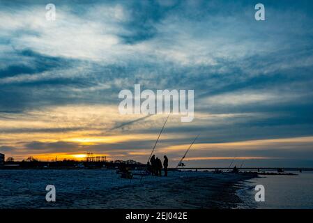 Surendorf, Deutschland. Februar 2021, 20th. Angler plaudern am Strand in Surendorf im Sonnenuntergang an der Eckernförder Bucht. Quelle: Axel Heimken/dpa/Alamy Live News Stockfoto