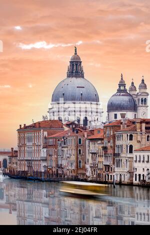 Atemberaubende Aussicht auf die Skyline von Venedig mit dem Canal Grande und der Basilika Santa Maria della Salute in der Ferne bei einem dramatischen Sonnenaufgang. Stockfoto