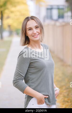 Schöne mittlere Alter kaukasischen Frau mit kurzen Haaren zu Fuß im Herbst Straße im Freien. Junge Frau mit kurzem Haarschnitt in Freizeitkleidung im Park Stockfoto