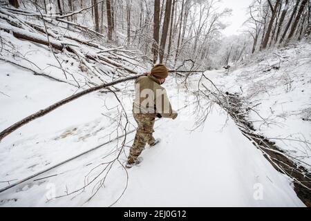 Ceredo, Usa. Februar 2021, 19th. Ein US-Soldat mit der West Virginia National Guard löscht Trümmer von einem Wintersturm von einer Straße 19. Februar 2021 in Ceredo, Wayne County, West Virginia. Ein großes Wintersturmsystem zu Beginn der Woche ließ mehr als 90.000 Einwohner von West Virginia in der gesamten Region ohne Strom zurück, fällte Bäume und machte abgelegene Straßen unpassierbar. Quelle: Planetpix/Alamy Live News Stockfoto