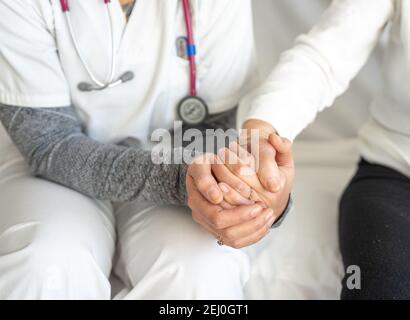 Hoher Winkel der Ernte anonymen Sanitäter hält Hand des Senior Frau, während sie zusammen auf der Couch sitzt Stockfoto