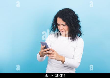 Brunette Mädchen sieht überrascht an ihrem Handy-Bildschirm Stockfoto