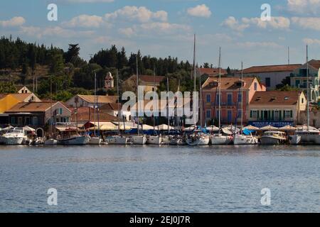 Segelboote säumen die Marina in Fiskardo, Kefalonia, Griechenland, mit einem blauen Himmel und weißen Wolken, mit Kopierraum Stockfoto