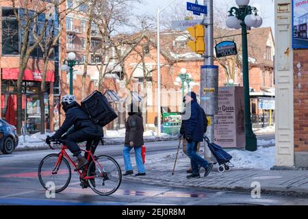 Ottawa, Ontario, Kanada - 6. Februar 2021: In Somerset Village laufen und radeln die Menschen durch die Kreuzung von Somerset und Bank Streets. Einige von t Stockfoto