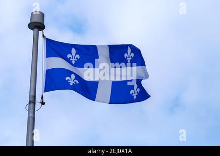 Die Flagge der kanadischen Provinz Quebec, die auf einem Fahnenmast fliegt. Stockfoto