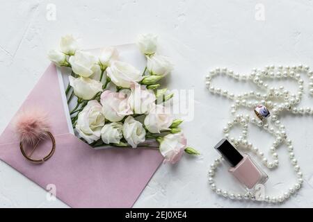 Luxus romantischen Hintergrund: Weiße Blumen, Perlen Halskette, Parfüm, Grußkarte auf weiß.Accessoires und Blumen. Online-Shopping oder Dating-Konzept Stockfoto