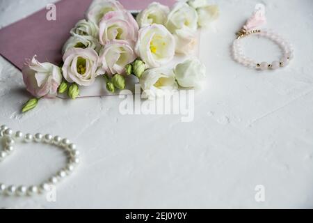 Luxus romantischen Hintergrund: Weiße Blumen, Perlen Halskette, Parfüm, Grußkarte auf weiß.Accessoires und Blumen. Online-Shopping oder Dating-Konzept Stockfoto