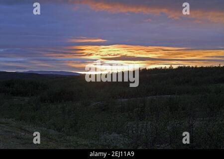 Norwegen, Norwegen; Dunkelblaue und pastellfarbene Wolken, die von der tief liegenden Sonne in der Tundra Nordnorwegens hinter dem Polarkreis erleuchtet werden. wieczór Stockfoto