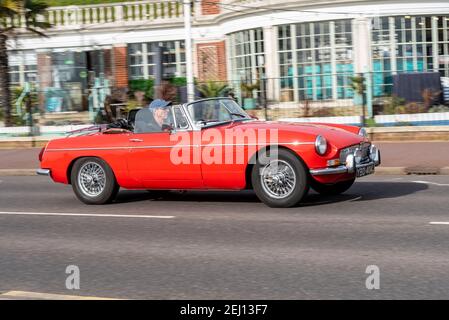 MG MGB Roadster Oldtimer fahren in Westcliff on Sea, Southend, Essex, Großbritannien, vorbei an historischer Architektur der umgebauten Strandhütte. 1970 J reg Stockfoto