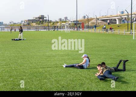 Kasan, Russland-26. September 2020: Bewohner der Stadt entspannen und spielen mit Kindern auf dem Rasen eines künstlichen Fußballplatz im Stadtpark auf t Stockfoto