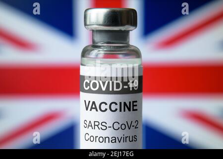 COVID-19-Impfstoff auf britischem Hintergrund, Flasche mit britischem Impfstoff für Coronavirus-Nahaufnahme. Konzept der Behandlung, klinische Studie, Verteilung und r Stockfoto