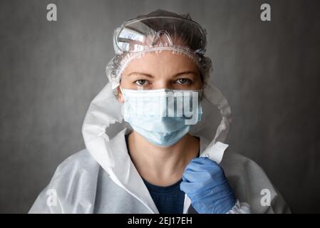 Ärztin oder Krankenschwester im PSA-Anzug, Porträt einer hübschen Frau mit Schutzbrille und medizinischer Gesichtsmaske aufgrund der COVID-19 Coronavirus-Pandemie. Co Stockfoto