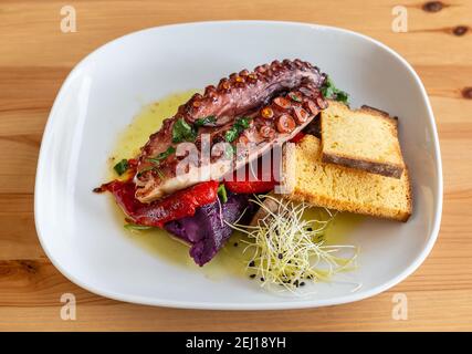 Einfache, aber fancy aussehende Platte aus lila Süßkartoffel, Pfeffer und Oktopus Beine mit Brot Toast auf der Seite. Stockfoto