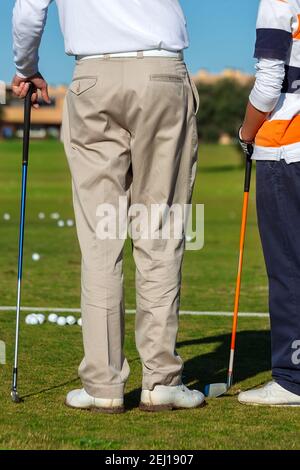 Rahmen von zwei Golfern, mit dem Rücken gedreht, diskutieren Golf, während sie ihre Schläger und viele Bälle auf dem Feld. Stockfoto