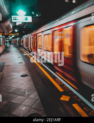 London UK Januar 2021 U-Bahn London U-Bahn nähert sich dem Bahnsteig, verschwommen in Bewegung mit langer Belichtung. Vertikale dunkle launische Aufnahme Stockfoto