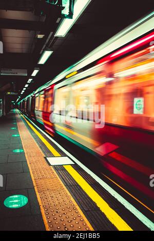 London UK Januar 2021 U-Bahn London U-Bahn nähert sich dem Bahnsteig, verschwommen in Bewegung mit langer Belichtung. Vertikale dunkle launische Aufnahme Stockfoto