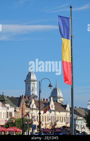 TURDA, RUMÄNIEN - 09. AUGUST 2015: Die rumänische Flagge winkt auf der Skyline der Innenstadt von Turda in Siebenbürgen Stockfoto