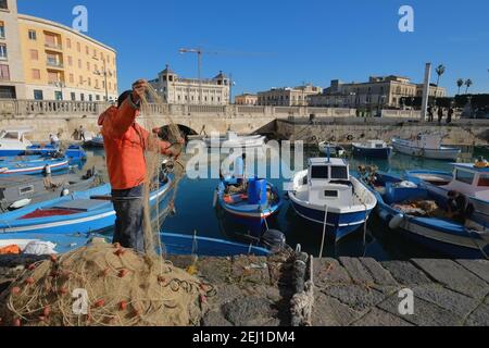 SIRACUSA, ITALIEN - JENUARY 03: Fischerboote und Fischerboote in der darsena von Ortigia, Altstadt von Siracusa auf Sizilien. Der Fischer im Vordergrund chec Stockfoto