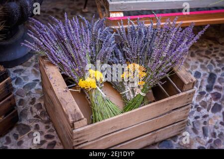 Lavendel-Blumensträuße mit gelben Blüten von Helichrysum stoechas verziert, in einer Holzkiste auf einem Blumenmarkt in Brihuega, Guadalajara Spanien Stockfoto