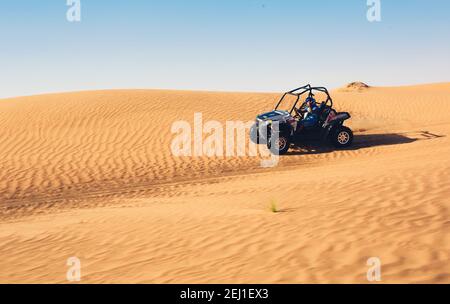 Quad Buggy Fahrradfahrer im Helm geht aus Sand Hügel in der Wüste Safari-Tour Stockfoto