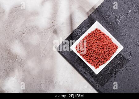 Achiote Körner in Holzschale auf weißem Hintergrund (Bixa orellana) Stockfoto