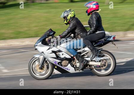Kawasaki Motorrad gefahren mit Pillion in Southend on Sea, Essex, UK mit Geschwindigkeit. Weibliche Reiten auf dem Rücken des Motorrads Stockfoto