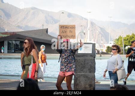 protestantischer protestant während eines Protestes gegen den Einsatz von Coronavirus-Masken in Teneriffa, Spanien, hält er ein Schild mit der Aufschrift „beim Essen werden Sie nicht infiziert“ Stockfoto
