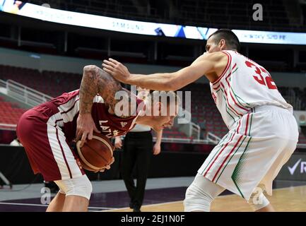 Riga, Lettland. Februar 2021, 20th. Janis Timma (L) aus Lettland steht mit Hristo Zahariev aus Bulgarien während ihres Qualifying-Basketballspiels FIBA EuroBasket 2022 in Riga, Lettland, am 20. Februar 2021, im Spiel. Kredit: Edijs Palens/Xinhua/Alamy Live Nachrichten Stockfoto