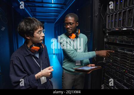 Porträt von zwei jungen Technikern, die den Server einrichten Netzwerk während der Arbeit im Rechenzentrum Stockfoto