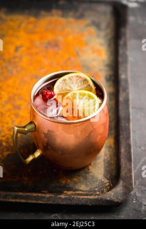 Süßes moscow Maultier mit Limette und Himbeere in Kupferbecher auf dem rustikalen Hintergrund. Selektiver Fokus. Geringe Schärfentiefe. Stockfoto