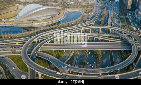 Atemberaubende Luftaufnahme aus einem hohen Winkel der entwickelten chinesischen Stadt. Mehrstufige erhöhte Verkehrsknotenpunkt, Gebäude des Open-Air-Musikparks Konzerthalle Stockfoto