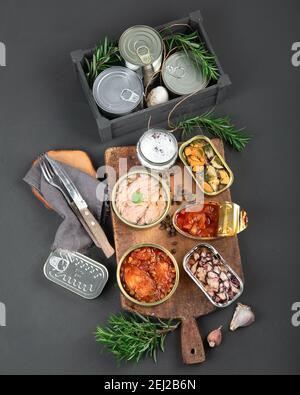 Verschiedene Fischkonserven und Meeresfrüchte in Aluminiumdosen. Auf dunkelgrauem Hintergrund. Draufsicht Stockfoto