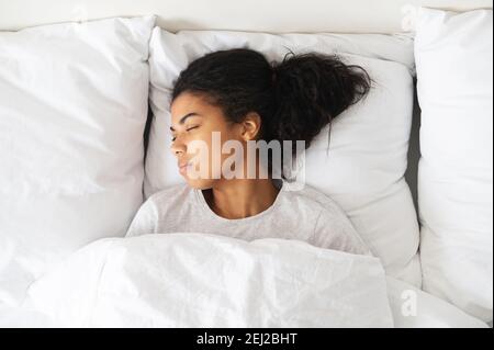 Gesunde friedliche Mädchen gut schlafen in komfortablen gemütlichen frischen Bett auf weichen Kissen weiße Bettwäsche orthopädische Matratze, genießen Sie zu Hause schlafen, Blick von oben Stockfoto