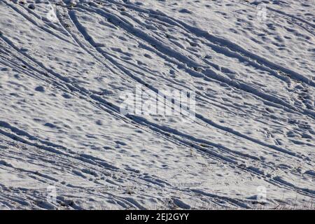 Viele Fußspuren, Ski- und Rodelbahnen auf einer Piste im Schnee Stockfoto