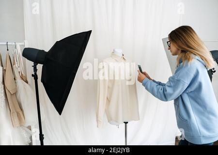 AR VR-Technologie in der Modeindustrie. Weibliche Designer Schrottung Kleidung auf Schaufensterpuppe per Handy für Augmented Reality Anwendung. AR VR-Lösungen Stockfoto