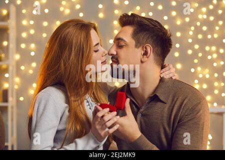 Glückliche junge Frau küsst ihren Freund, nachdem er sie gab Schöner Verlobungsring Stockfoto